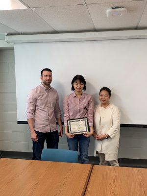 Lab members holding paper award with Professor Lee